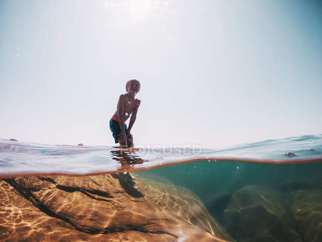 Мальчик, стоящий на скале в озере Сьюдад, США — стоковое фото