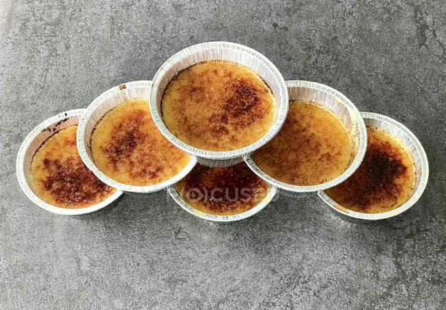 Silver foil ramekins with creme brulee, elevated view — Stock Photo
