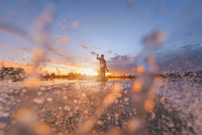 Silueta de un pescador que lanza una red de pesca en el río, Tailandia - foto de stock