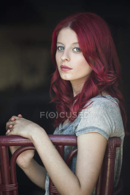 Retrato de uma mulher bonita com cabelo vermelho sentado em uma cadeira — Fotografia de Stock