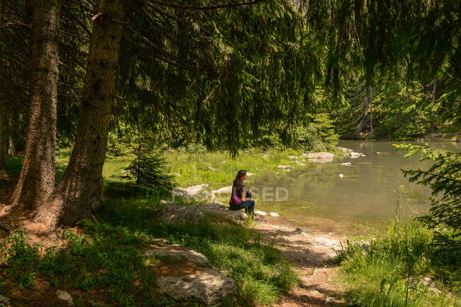 Frau sitzt im Sommer an einem baumbestandenen See, Bulgarien — Stockfoto