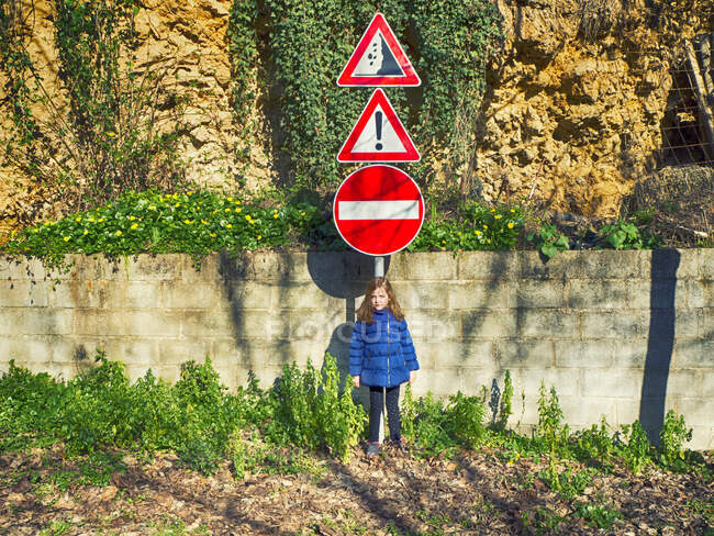 Chica de pie bajo una señal de tráfico en la calle, Abruzos, Italia - foto de stock