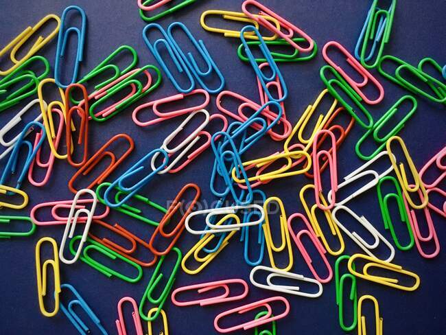 Multi coloured paper clips on a blue background — Stock Photo