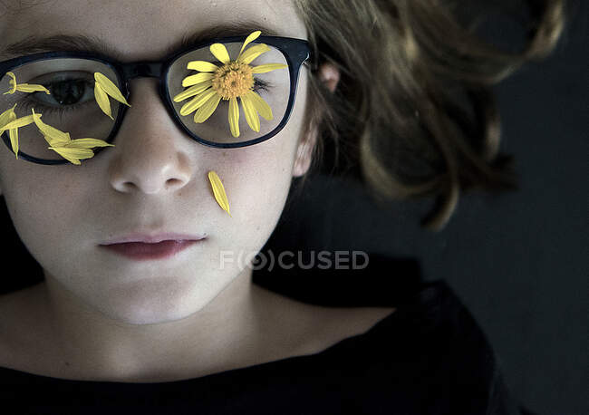 Retrato de una niña con pétalos de flores cubriendo sus gafas — Stock Photo