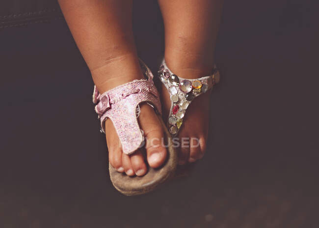Close-up de pés de uma menina usando sandálias incompatíveis — Fotografia de Stock