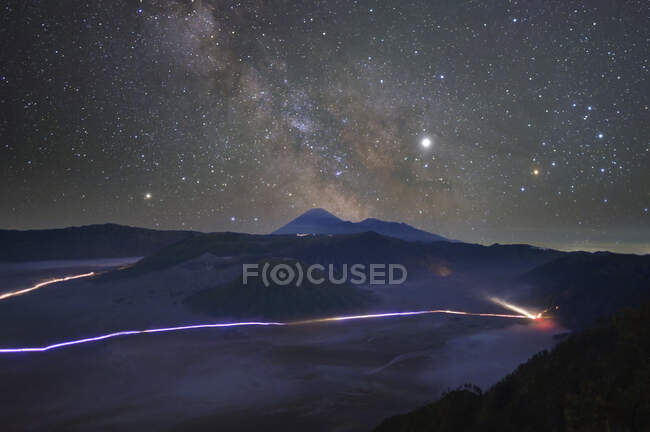 Aerial view of traffic light trails through mountains below the milky way, Thailand — Stock Photo