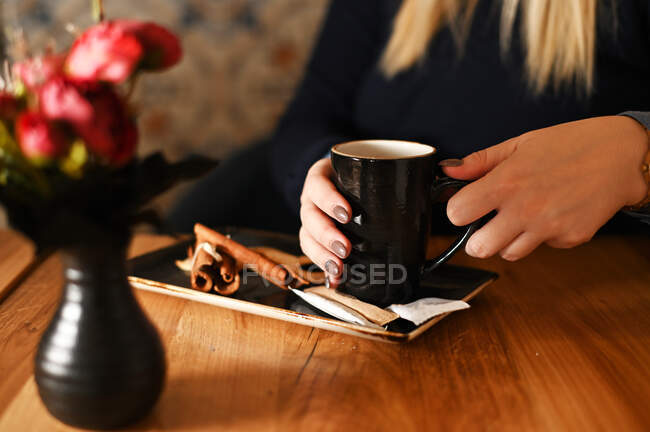 Mujer sentada en una mesa disfrutando de una taza de café - foto de stock