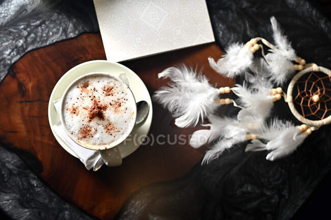 Overhead view of a dreamcatcher next to a cup of coffee on a table — Stock Photo