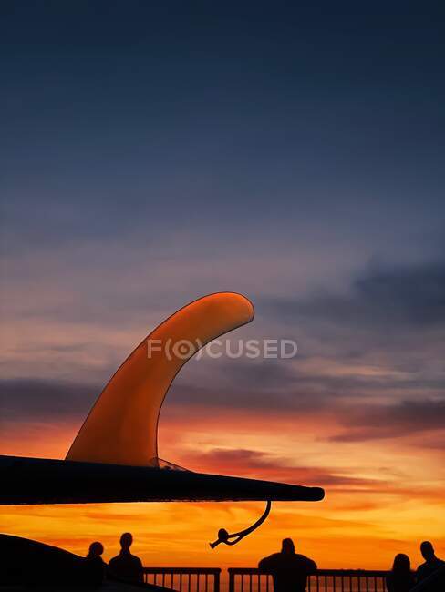 Silhouette d'une nageoire de planche de surf et des personnes regardant la vue sur l'océan au coucher du soleil, Californie, États-Unis — Photo de stock