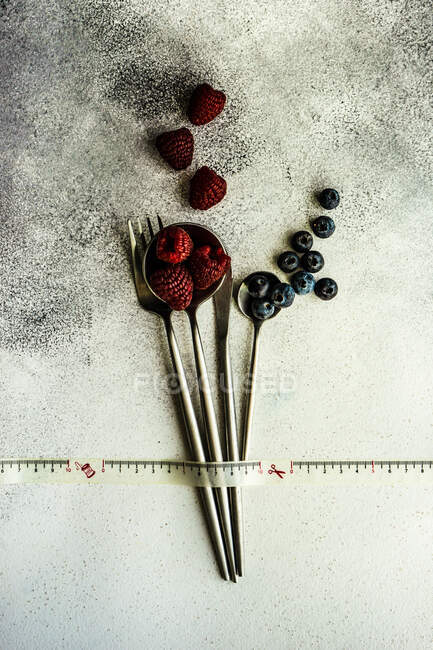 Свежие ягоды и ложки на деревянном фоне — стоковое фото