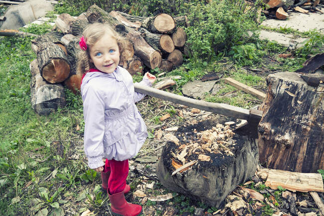Ragazza sorridente in piedi accanto a una catasta di legna e zona di taglio del legno, Polonia — Foto stock