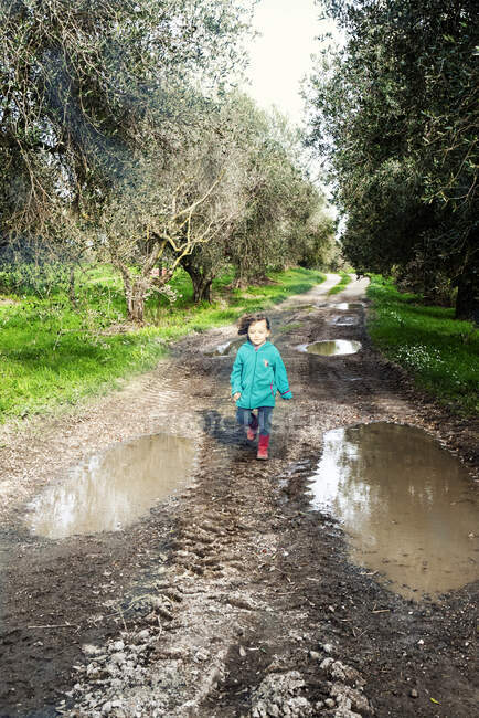Chica caminando por un sendero fangoso en el campo, Italia - foto de stock