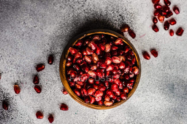 Pomegranate seeds in a bowl on a gray background. top view. copy space. — Stock Photo