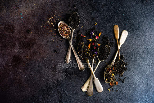 Té negro y hierbas secas sobre un fondo oscuro. - foto de stock