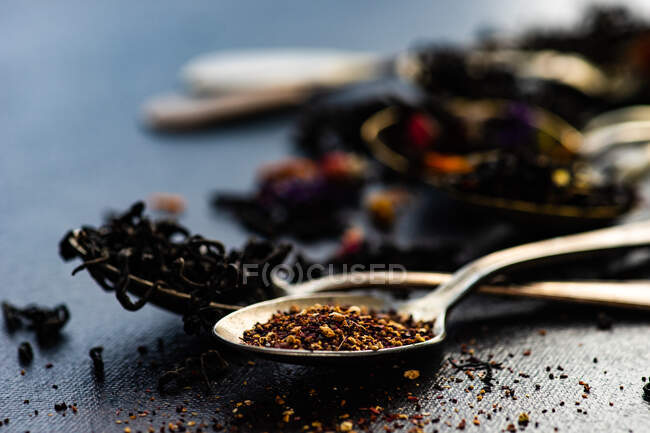 Schwarzer Tee und ein Löffel mit getrockneten Früchten und Kräutern — Stockfoto