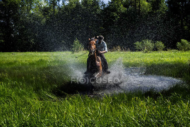 Homem montando um cavalo através de paisagem alagada, Polônia — Fotografia de Stock