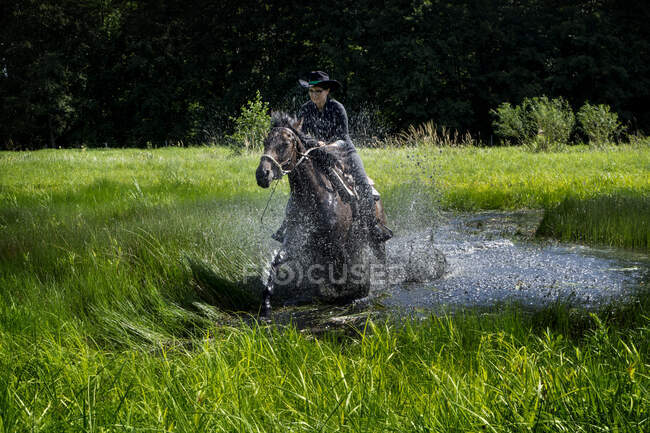 Ritratto di donna che cavalca attraverso un lago nel paesaggio rurale, Polonia — Foto stock