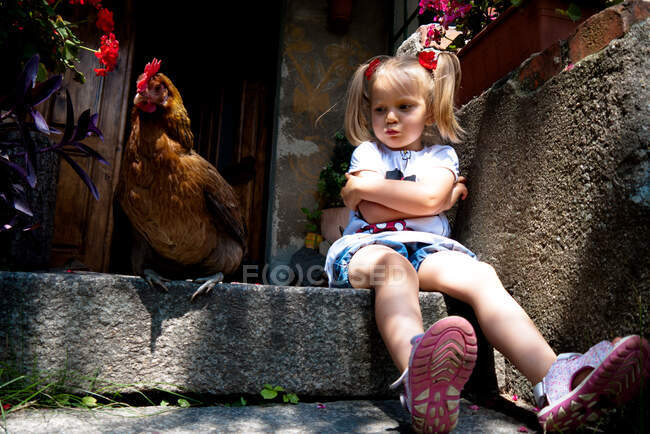 Бурхлива дівчинка сидить на сходах біля курки (Польща). — стокове фото