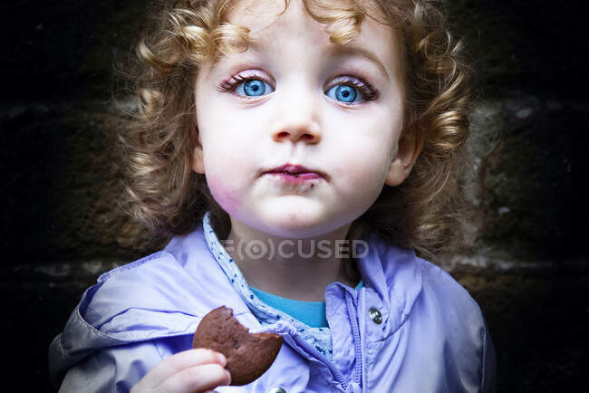 Retrato de uma menina comendo um biscoito de chocolate — Fotografia de Stock