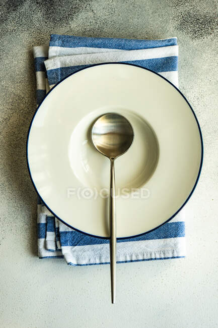 Overhead view of a spoon in a soup plate on a folded napkin — Stock Photo