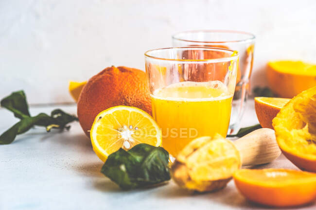 Suco de laranja e frutas cítricas em vidro e frutas frescas na mesa de madeira. — Fotografia de Stock