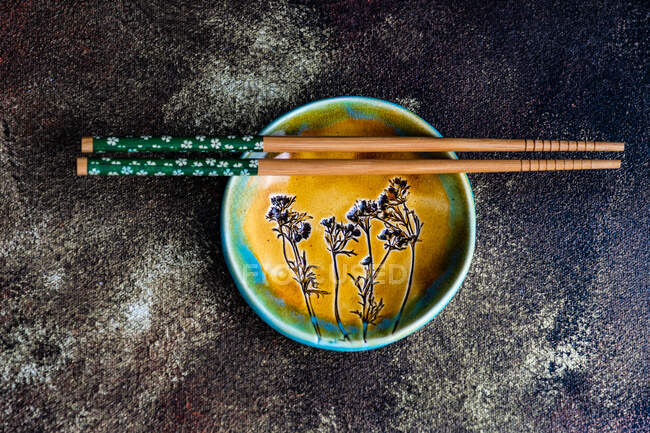 Top view of a plate with chopsticks and a wooden spoon on a black background — Stock Photo