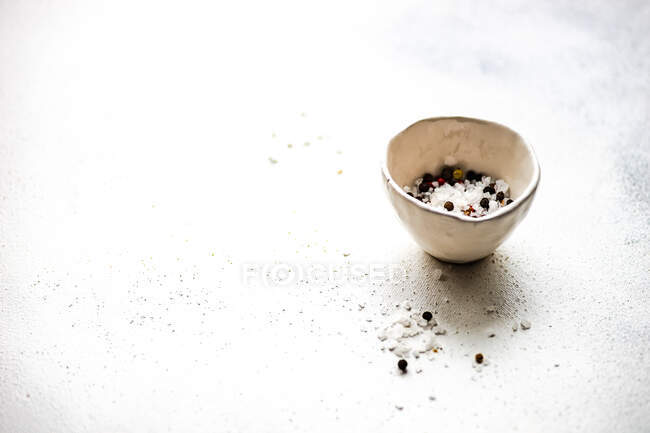 Cuenco de sal marina con granos de pimienta mezclados - foto de stock