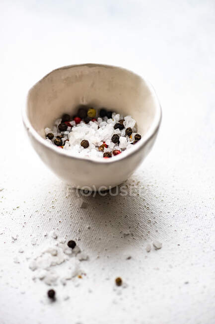 Close up of a bowl of white and black pepper on a light background — Stock Photo