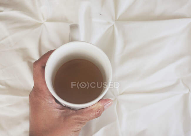 Overhead view of a hand holding a cup of tea — Stock Photo