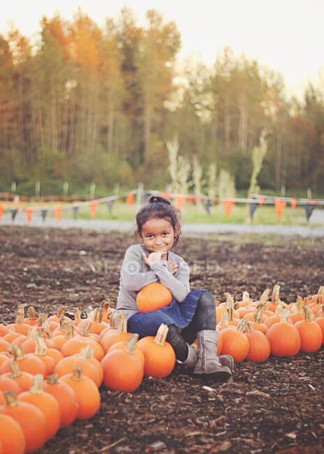 Menina sorridente sentada em um remendo de abóbora no outono, Washington, EUA — Fotografia de Stock