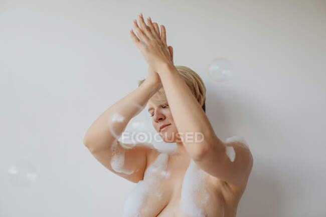 Frau mit Seifenlauge bedeckt, die Arme in der Luft — Stockfoto