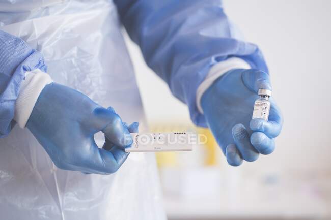 Enfermeira segurando um frasco para injetáveis da vacina contra o coronavírus e um dispositivo de teste PCR rápido — Fotografia de Stock