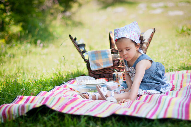Chica sentada en una manta de picnic en el parque, Bulgaria - foto de stock