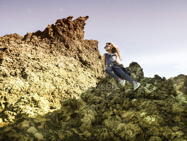 Menina sentada em rochas vulcânicas olhando para a vista, Lanzarote, Ilhas Canárias, Espanha — Fotografia de Stock