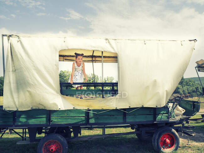Девушка, стоящая на старой телеге, глядя через отверстие, Венгрия — стоковое фото