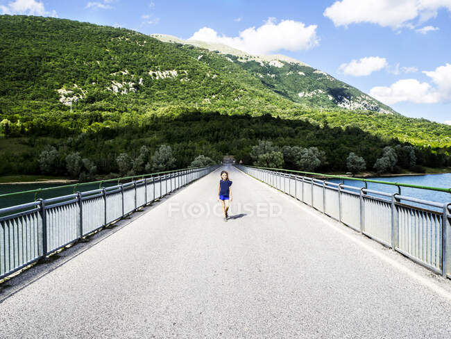 Girl walking across a bridge on Lake Barrea, L'Aquila, Abruzzo, Italy — Stock Photo