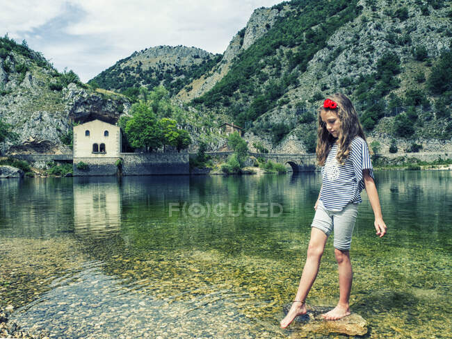Niña parada sobre una roca en Lago di San Domenico, L 'Aquila, Abruzzo, Italia - foto de stock