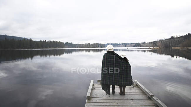 Rear view of two girls standing on a dock wrapped in a blanket, Washington State, USA — Stock Photo