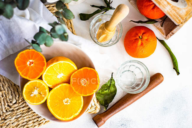 Zumo de naranja fresco con limón y menta sobre un fondo de madera blanca. - foto de stock