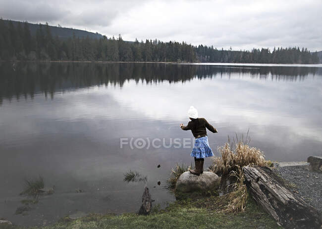 Menina jogando pedras em um lago, Estado de Washington, EUA — Fotografia de Stock