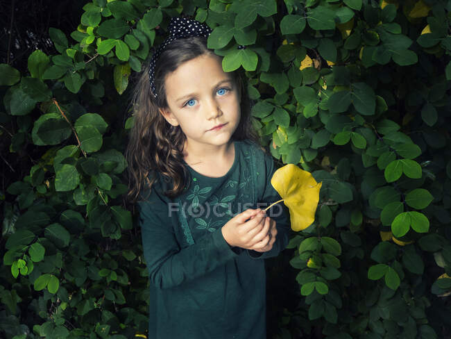 Mädchen steht an einem Busch und hält ein Blatt, Italien — Stockfoto