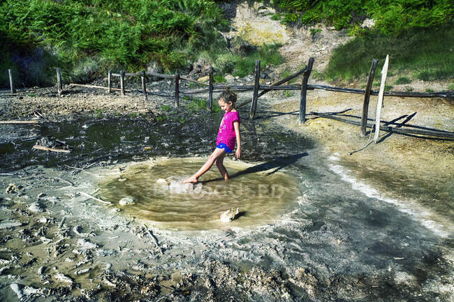 Girl standing in a  sulphur spring kicking water, Monterano, Italy — Stock Photo