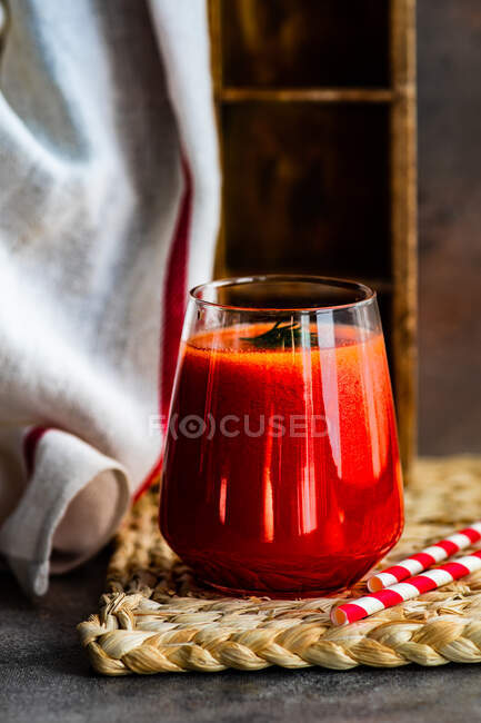 Vin rouge dans un verre avec une paille sur un fond en bois — Photo de stock