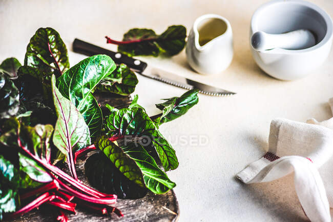 Rohe Rote-Bete-Blätter auf einem Holzschneidebrett mit Olivenöl — Stockfoto