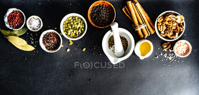 Вид зверху на палички кориці, волоські горіхи, гарбузове насіння, сіль, перець і лаврове листя на столі — стокове фото