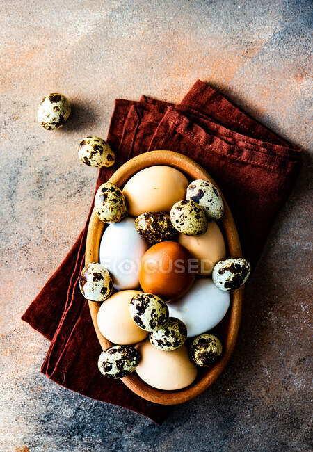 Bol d'oeufs et oeufs de caille sur une serviette pliée sur une table — Photo de stock