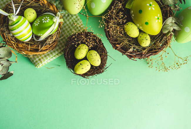 Overhead view of Easter eggs in a bird's nest on a green background — Stock Photo