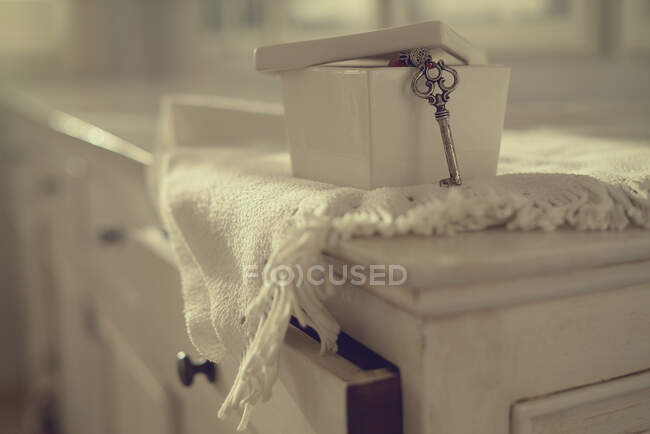 Close-up of a key hanging out of a ceramic box on a chest of drawers — Stock Photo