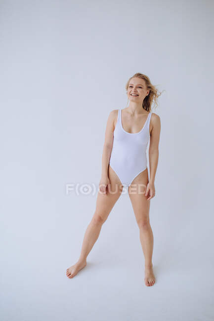 Smiling female gymnast in a white leotard in a studio — Stock Photo