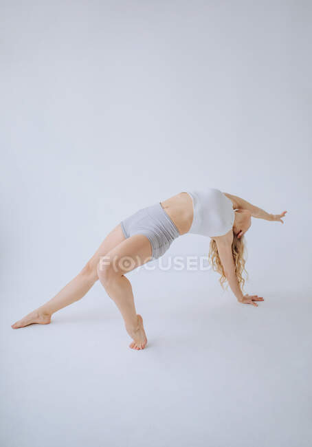 Female gymnast doing a back bend in a studio — Stock Photo